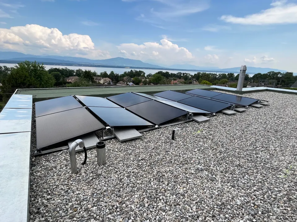 Modules solaires noirs sur le toit plat d’une maison individuelle à Crans-près-Céligny (environs : lac)