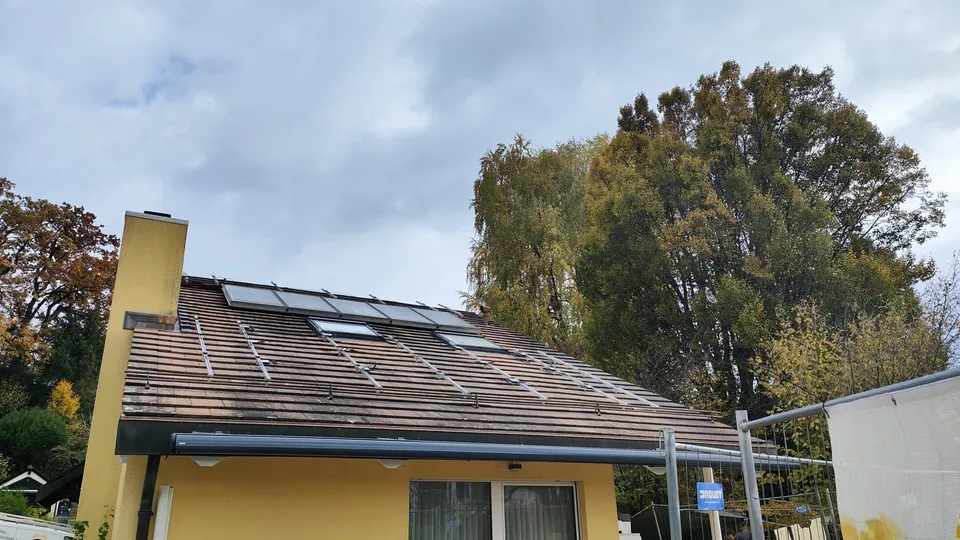 Modules solaires noirs sur le toit en tuiles d’une maison individuelle à Prilly (environs : arbres) – autre vue