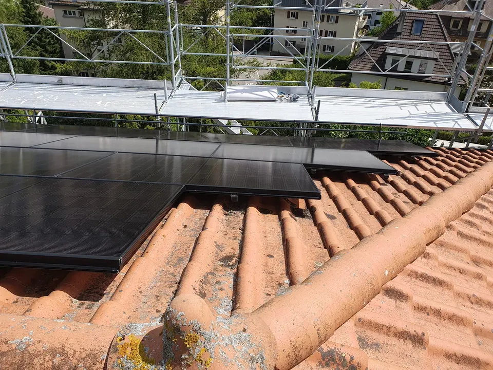 Schwarze Solarmodule auf dem roten Ziegeldach eines Mehrfamilienhauses in Freiburg (Umgebung: Stadtquartier)