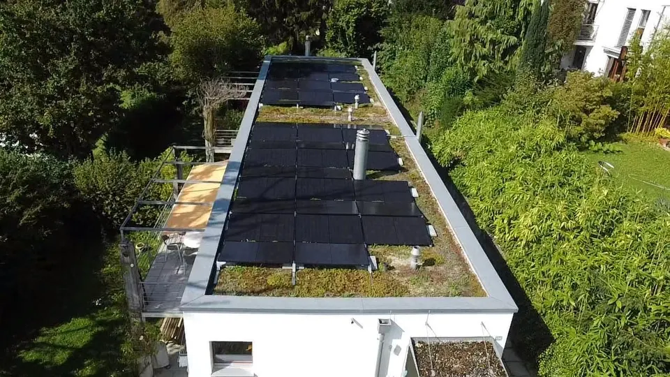 Vue aérienne : modules solaires noirs sur le toit plat d’une maison individuelle à Villars-sur-Glâne (environs : jardin, arbres)