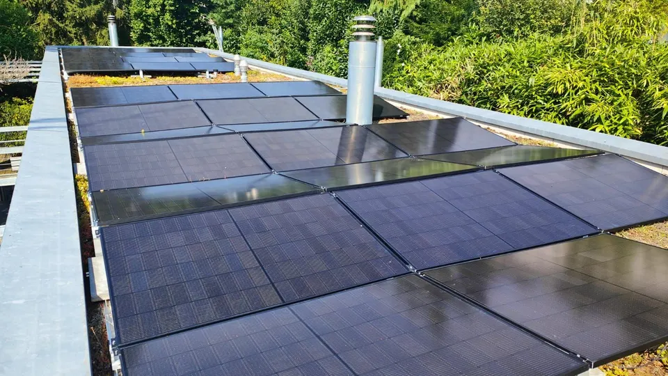 Modules solaires noirs sur le toit plat d’une maison individuelle à Villars-sur-Glâne (environs : jardin)