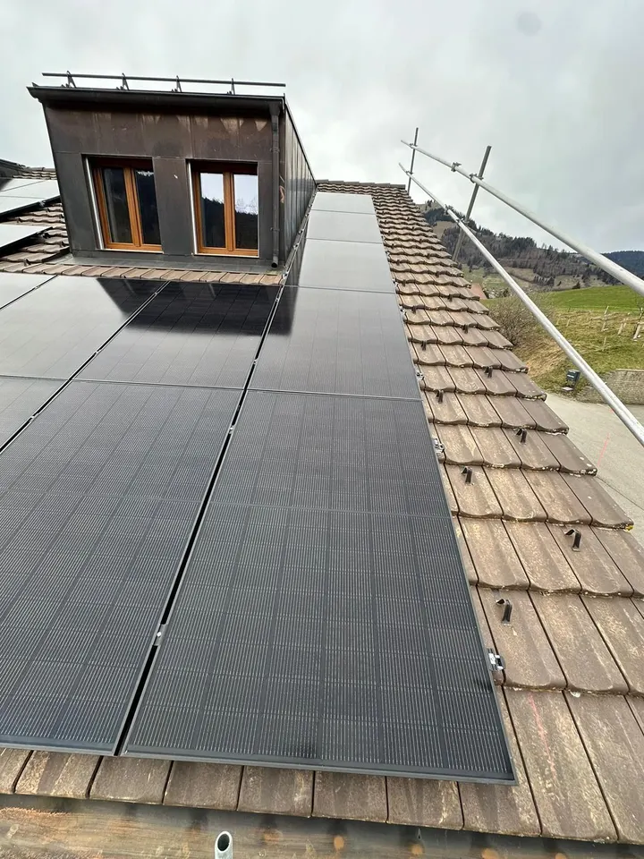 Schwarze Solarmodule auf dem Ziegeldach einer Wohnanlage im Stockwerkeigentum in Charmey