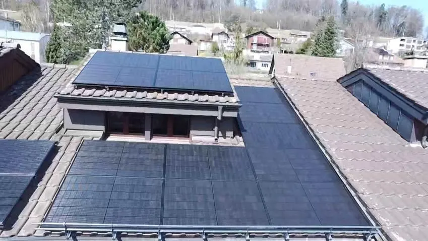 Modules solaires noirs sur le toit en tuiles d’une maison individuelle à Matran (environs : maisons voisines)