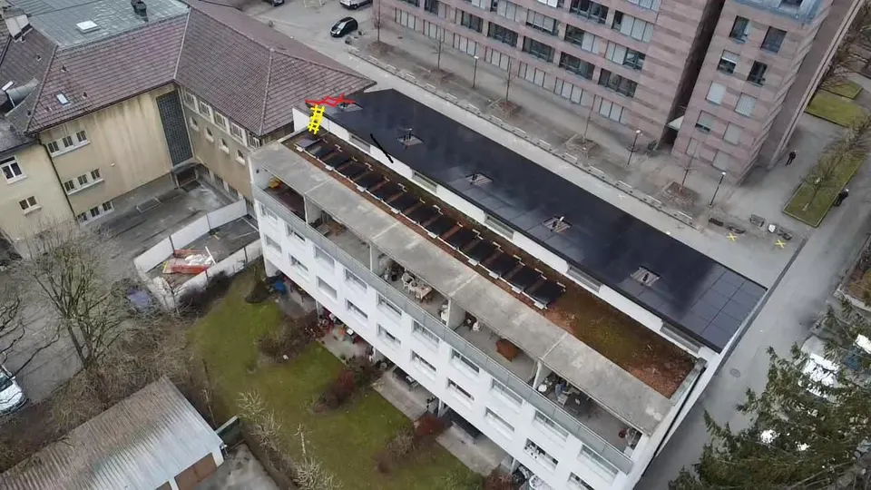 Luftbild: Mehrfamilienhaus in Freiburg mit schwarzen Solarmodulen auf dem ganzen Dach, umgeben von Stadthäusern