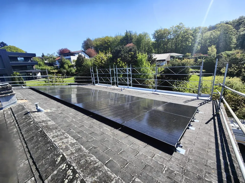 Modules solaires noirs sur le toit en bardeaux d’une maison individuelle à Villars-sur-Glâne (environs : arbres)