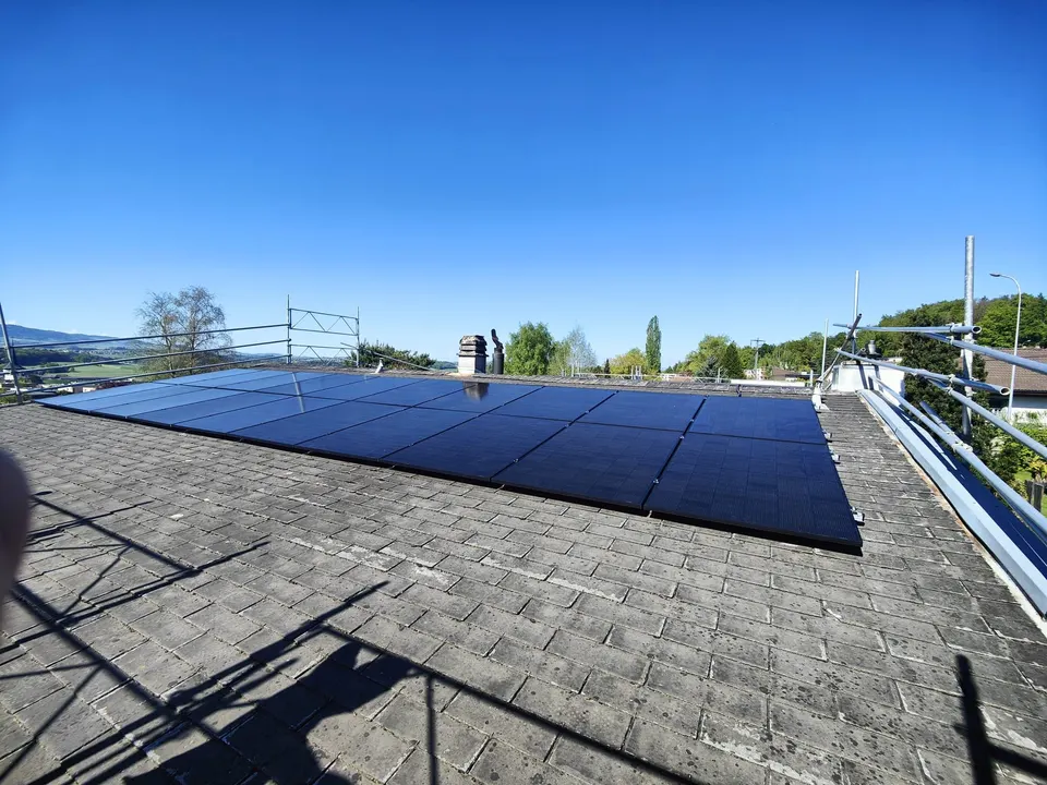 Modules solaires noirs sur le toit en bardeaux d’une maison individuelle à Villars-sur-Glâne (environs : maisons voisines)