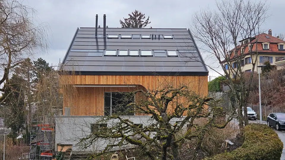 Toiture solaire intégrée noire avec fenêtres de toit sur l’immeuble à Fribourg
