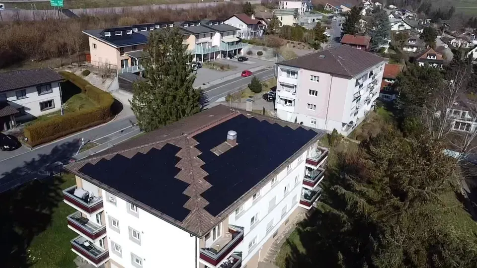 Luftbild: schwarze Solarmodule auf dem dunklen Ziegeldach eines Einfamilienhauses in Matran (Umgebung: Nachbarhäuser)