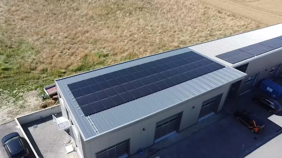 Luftbild: schwarze Solarmodule auf dem Blechdach einer Halle in Cournillens (Umgebung: Wiesen)