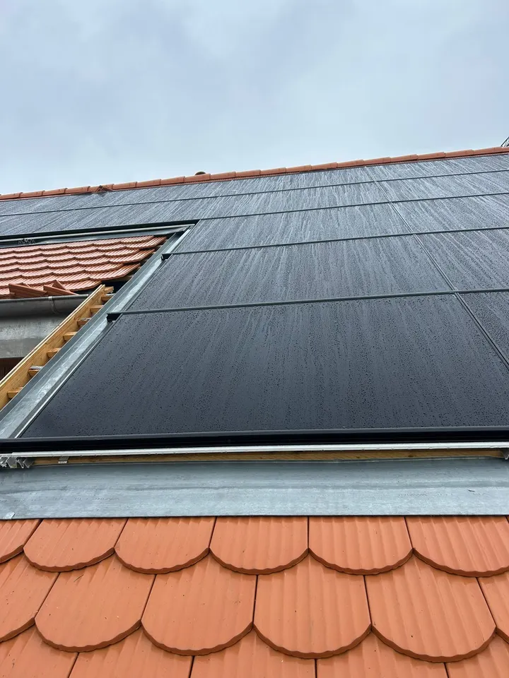 Modules solaires noirs sur le toit en tuiles rouges d’un immeuble à Chevilly