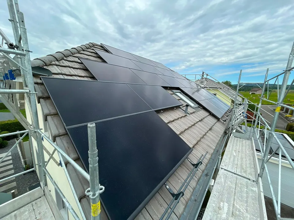 Modules solaires noirs sur le toit en tuiles grises d’une maison individuelle à Meisterschwanden – échafaudage encore en place