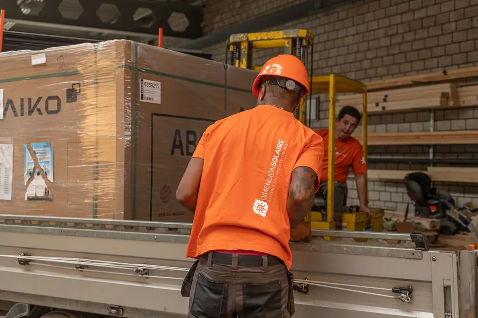 Monteur von Dimension Solaire mit einer Palette Solarmodule im Lager